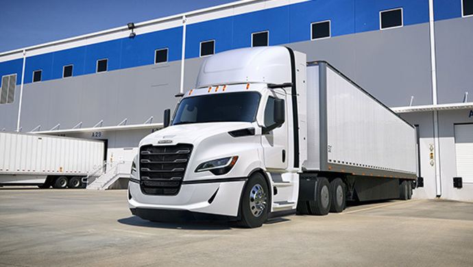White Cascadia tractor-trailer parked at loading dock of distribution center